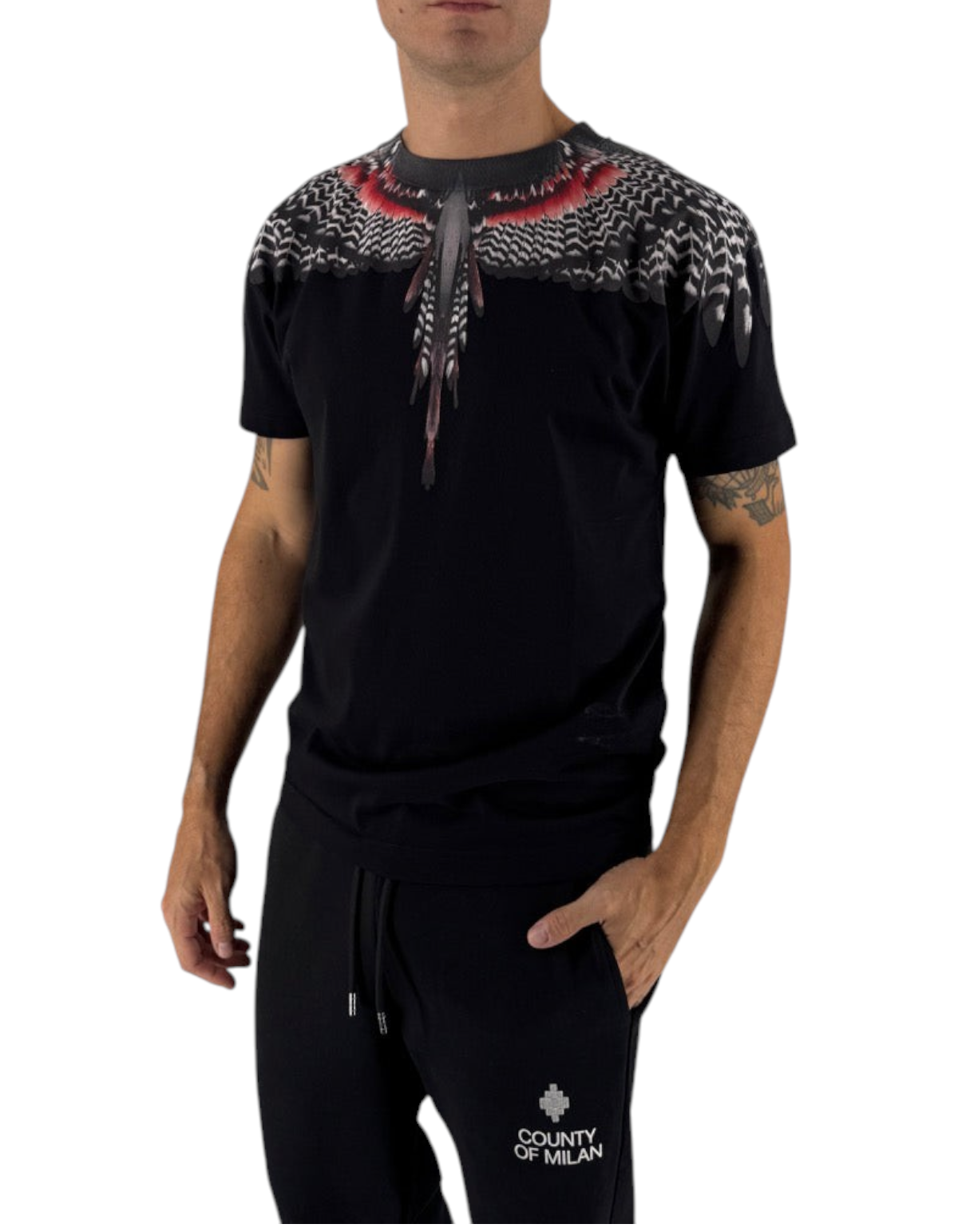 Modello indossa t-shirt nera in cotone Marcelo Burlon County Of Milan con iconica stampa piumata su DevidLabel
