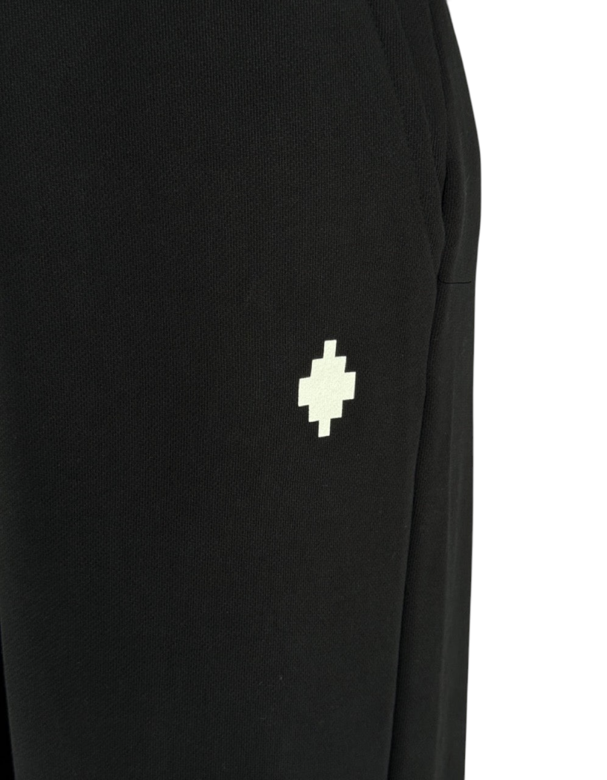Dettaglio del pantalone oversize in felpa nero DevidLabel con logo a croce bianco ricamato