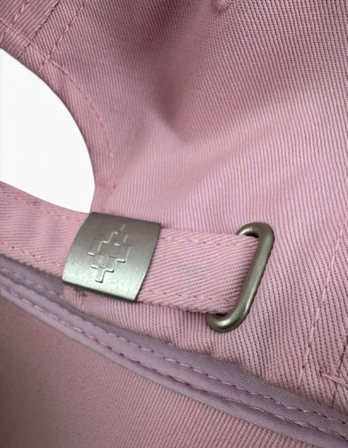 Dettaglio della fibbia metallica con logo sul retro del cappellino baseball rosa DevidLabel in cotone