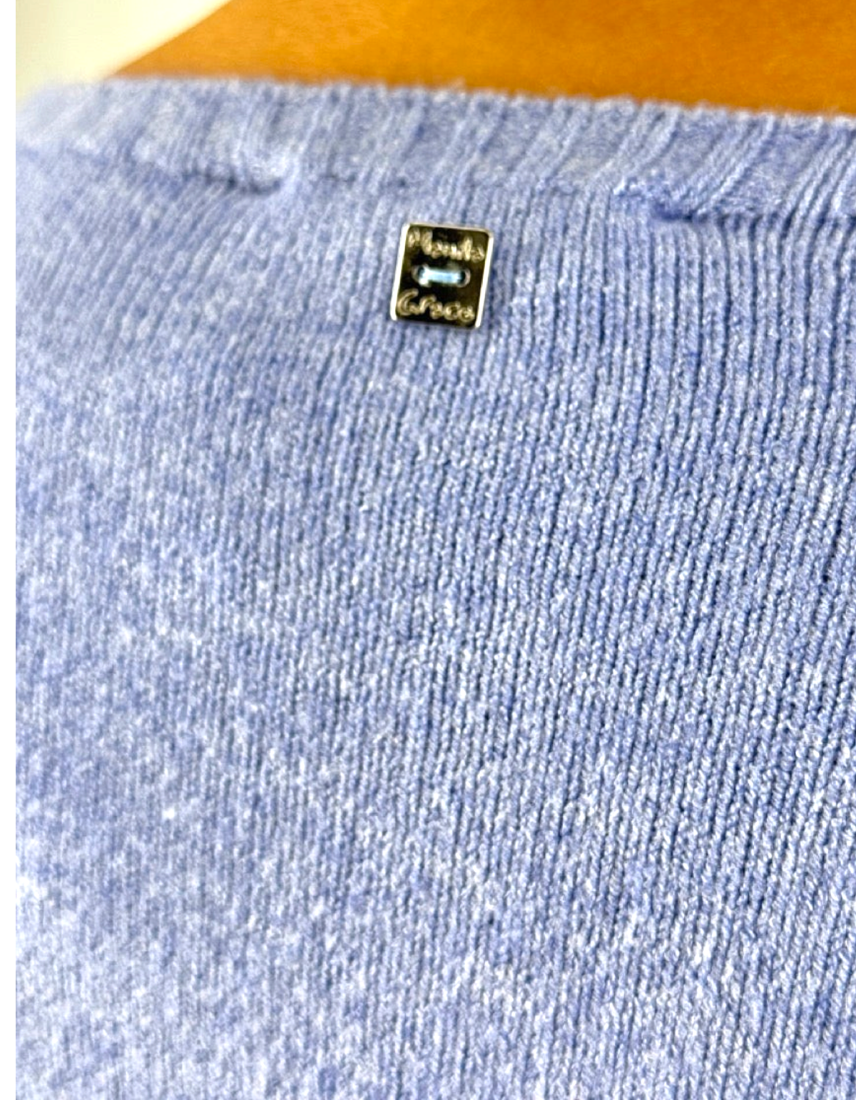 Dettaglio del maglione Manila Grace color viola con logo metallico sul retro dello scollo a barca