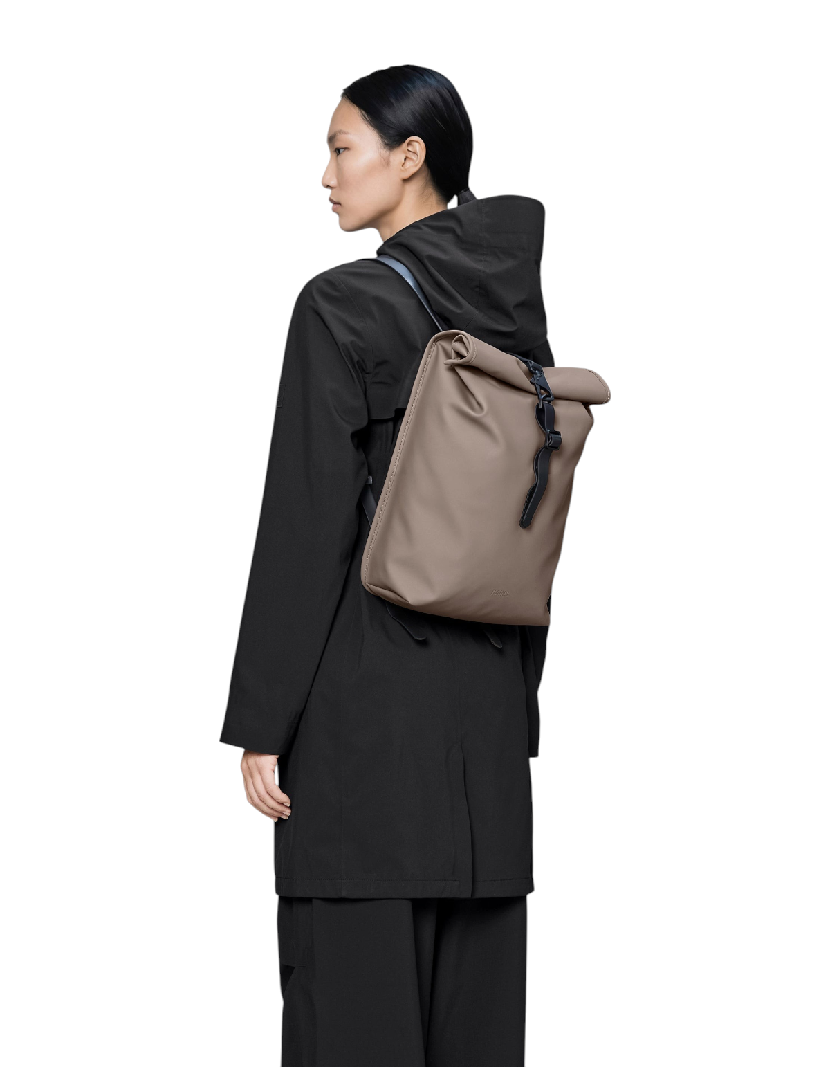 Modella indossa zaino Rains Rolltop Rucksack Mini colore Cinder in tessuto impermeabile da DevidLabel