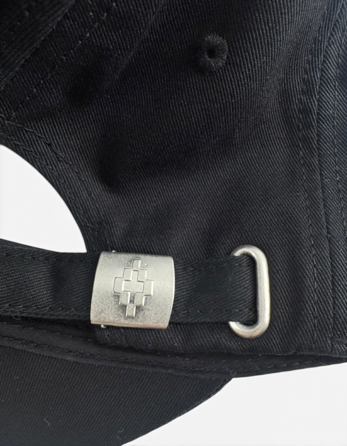 Dettaglio della fibbia metallica con logo inciso sul retro del cappellino baseball DevidLabel nero in cotone