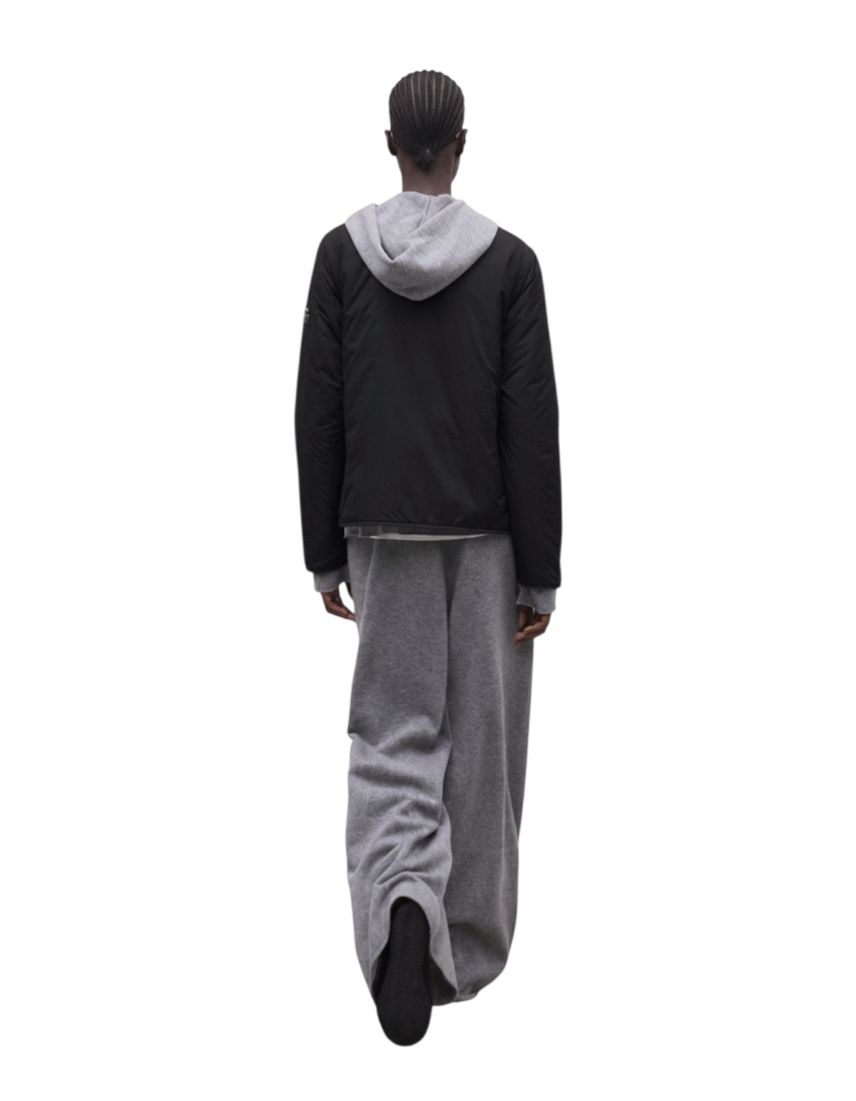 Modella di spalle indossa la giacca nera Monica di DevidLabel con cappuccio grigio e pantaloni ampi coordinati