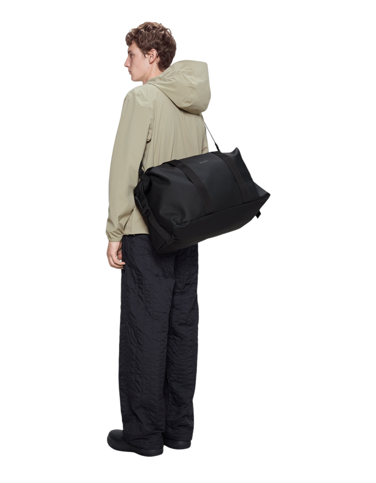 Modello indossa il borsone nero DevidLabel Rains Hilo Weekend Bag impermeabile con tracolla su sfondo neutro