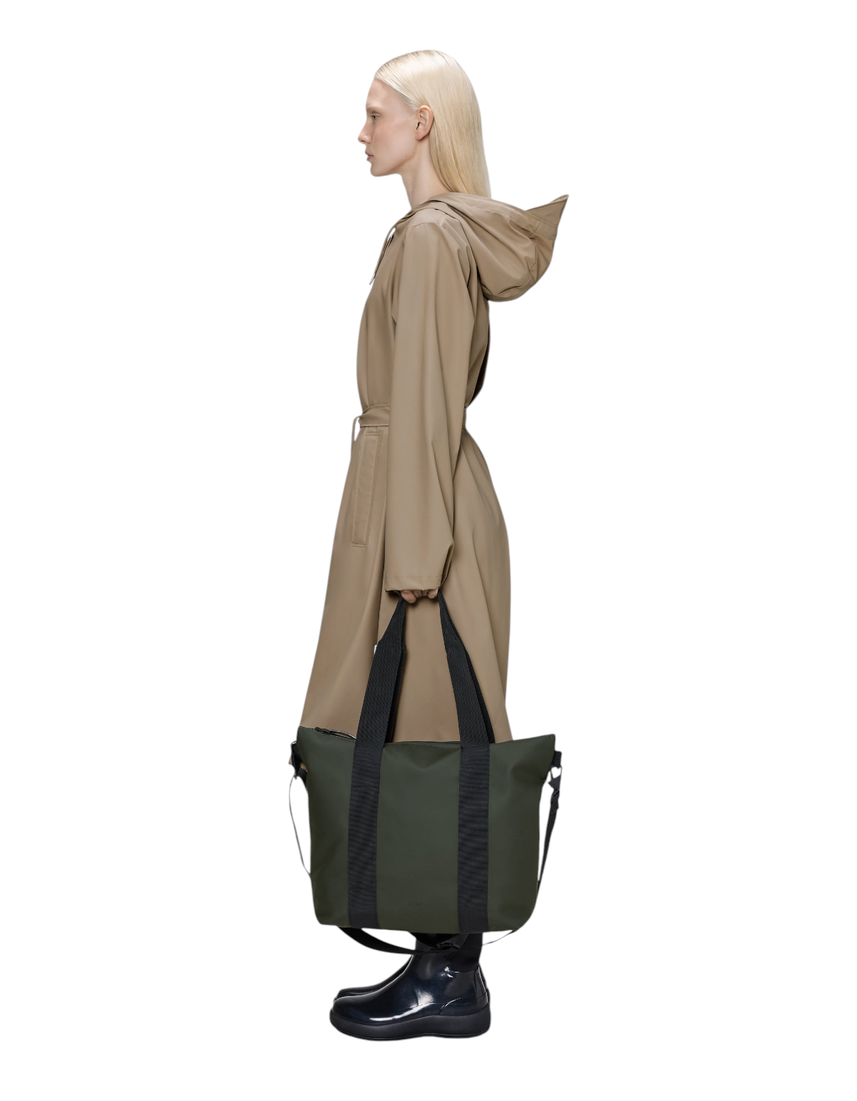 Modella di profilo con DevidLabel Rains Tote Bag Mini verde in tessuto impermeabile con manici neri e tracolla