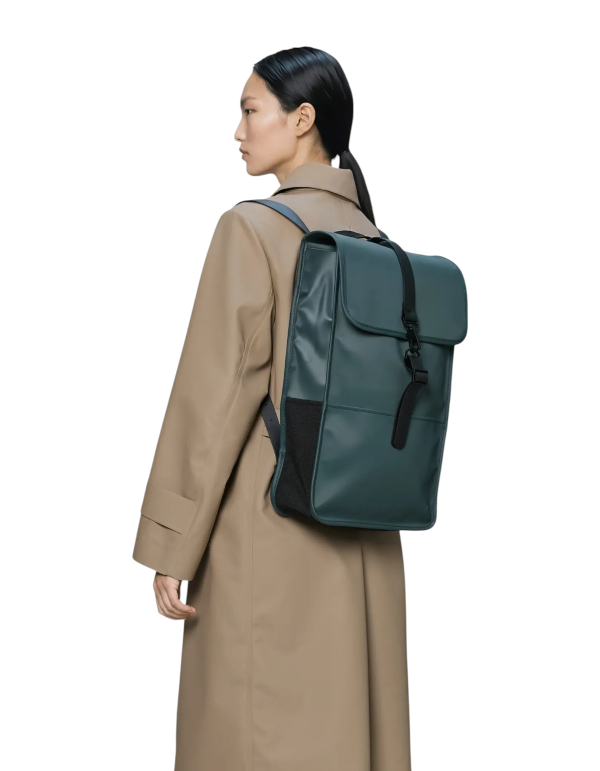 Modella indossa zaino impermeabile Rains Backpack Mystique color verde scuro con chiusura a gancio su cappotto beige