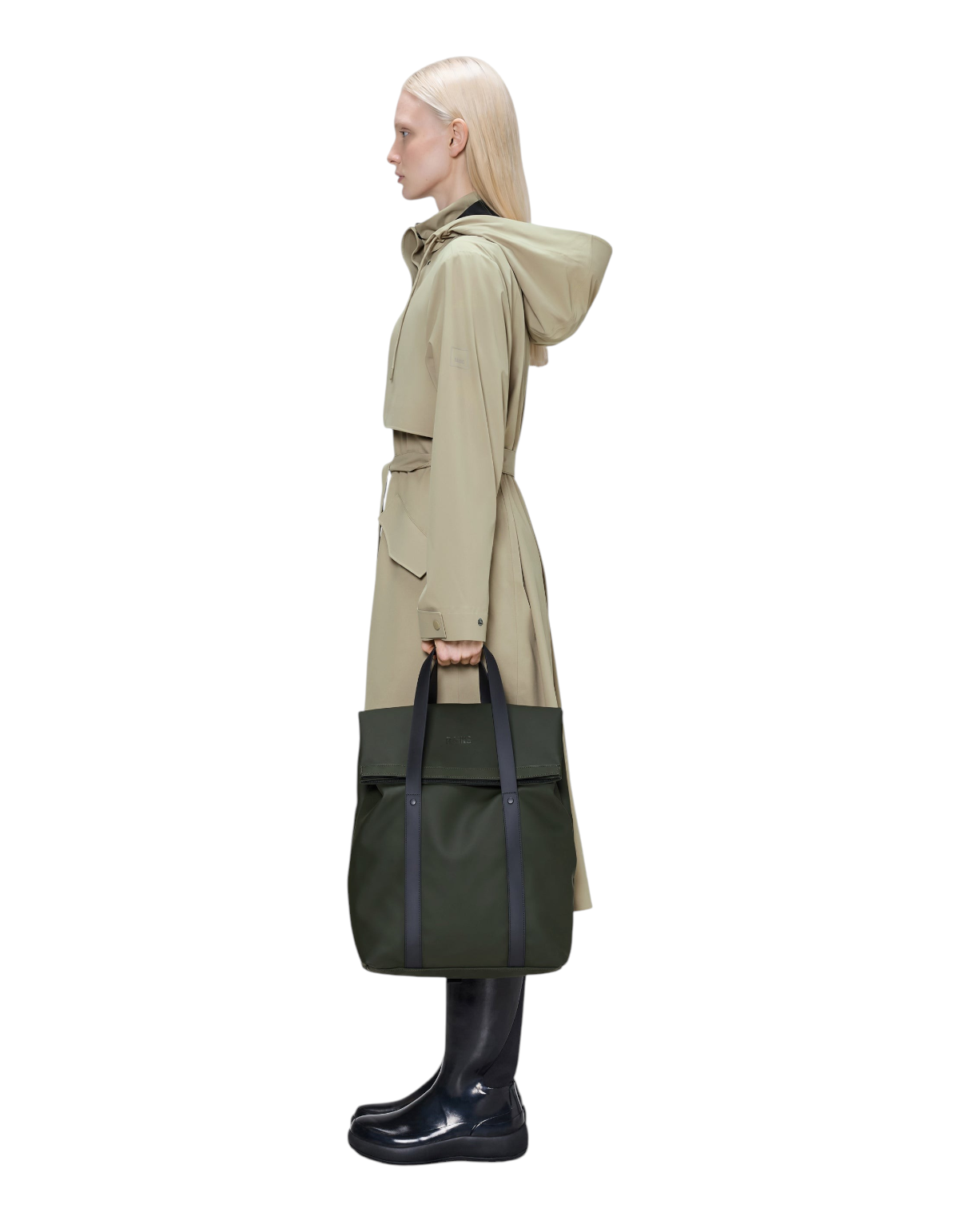 Modella di profilo indossa lo zaino tote Rains 2 Way Tote Backpack verde in tessuto impermeabile da DevidLabel