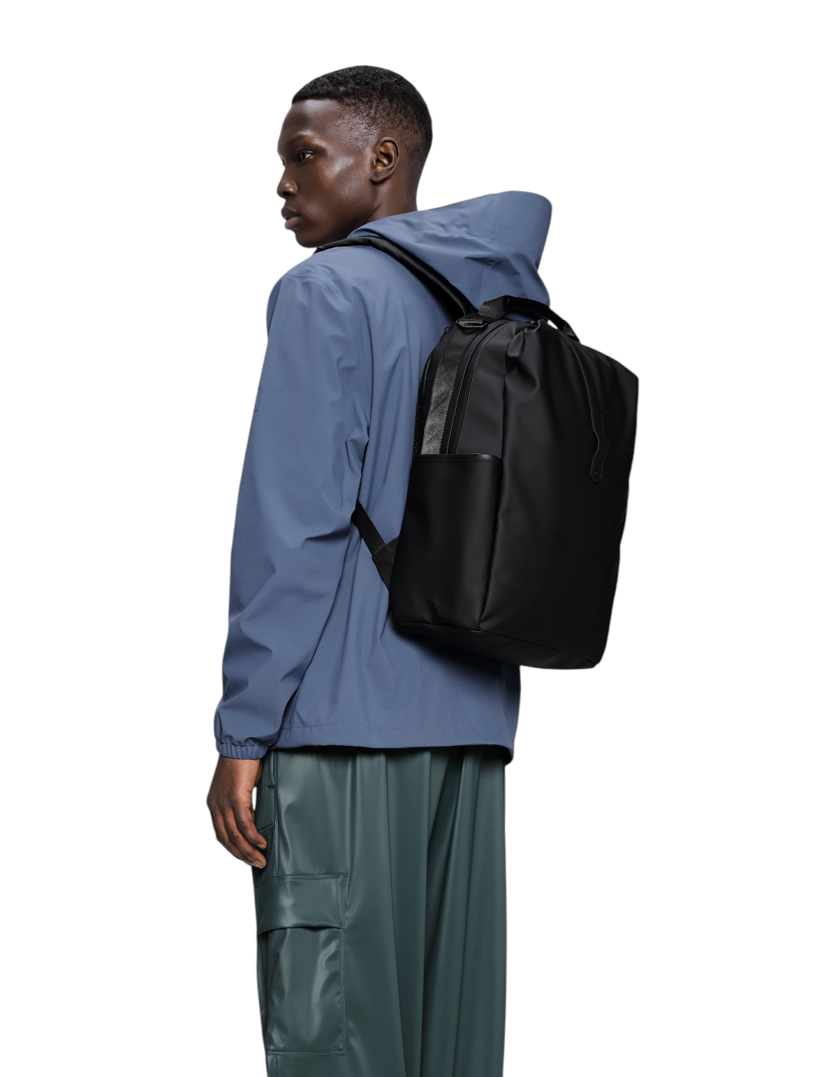 Modello indossa zaino impermeabile nero Rains Clip Front Backpack di DevidLabel con spallacci imbottiti e chiusura clip