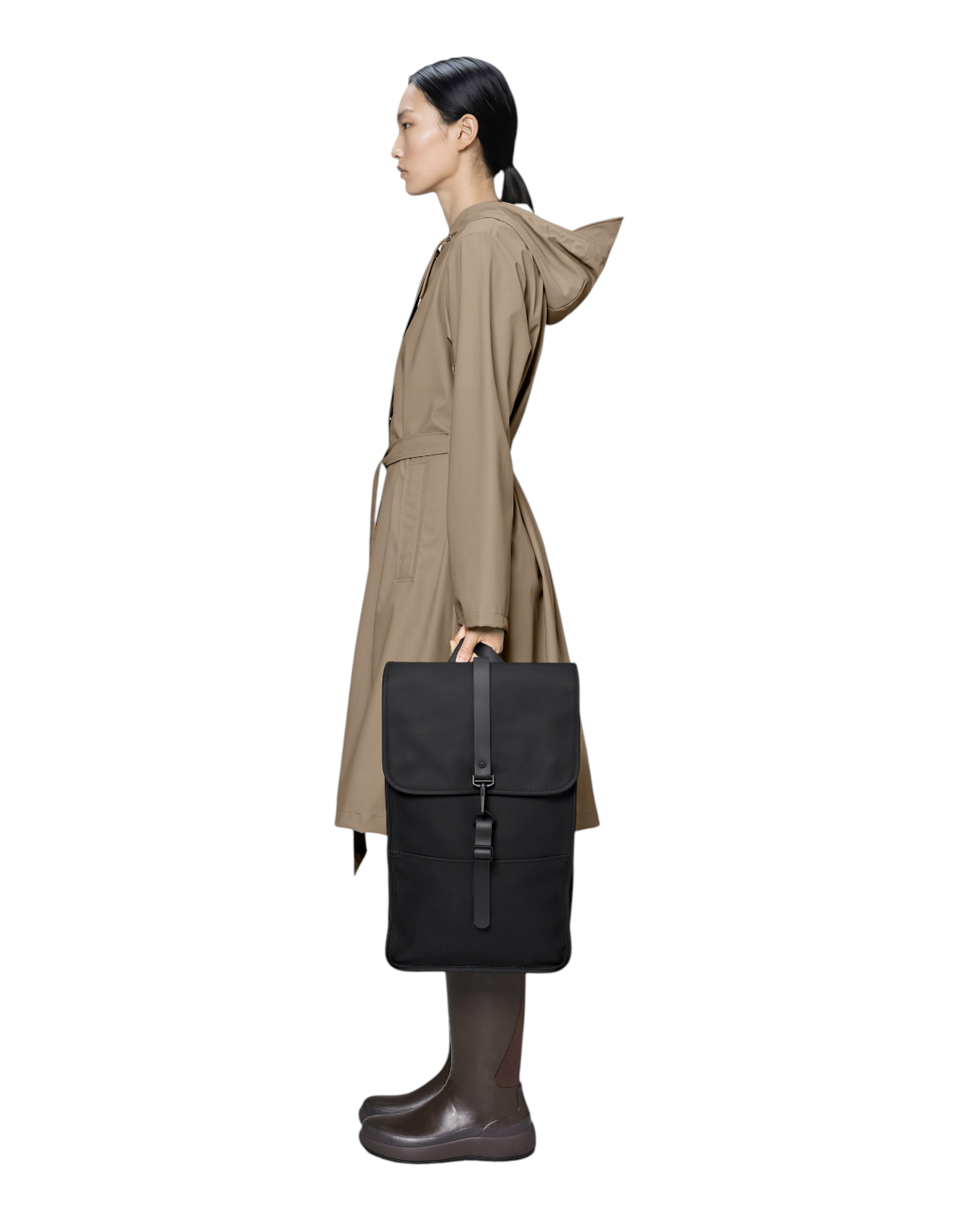 Modella di profilo indossa un impermeabile beige e tiene in mano lo zaino nero DevidLabel Backpack W3 impermeabile
