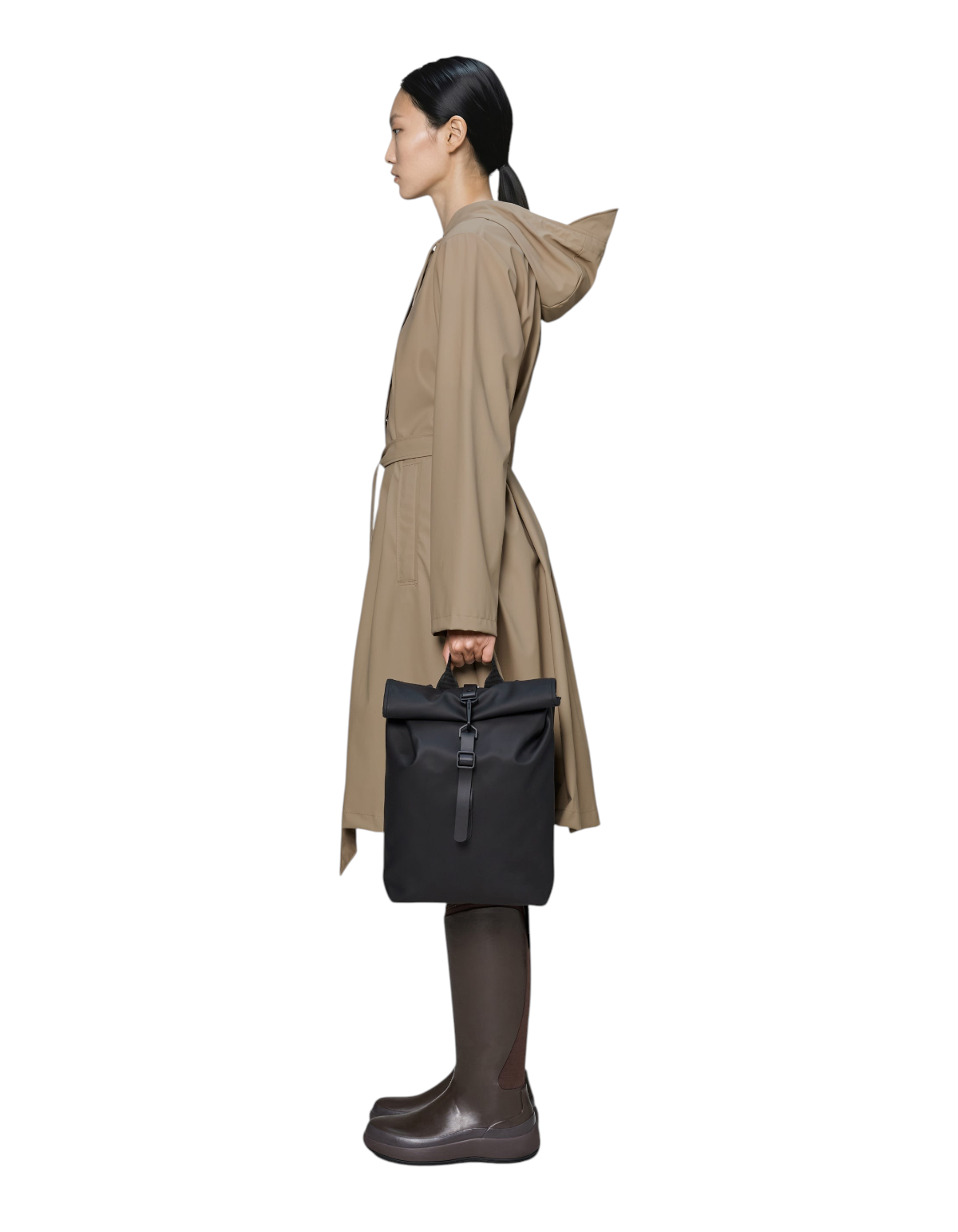 Modella di profilo indossa zaino nero Rains Rolltop Rucksack Mini impermeabile in tessuto PU venduto da DevidLabel